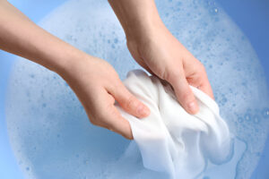 A bowl of white laundry soaking in baking soda water as part of a natural whitening tip.